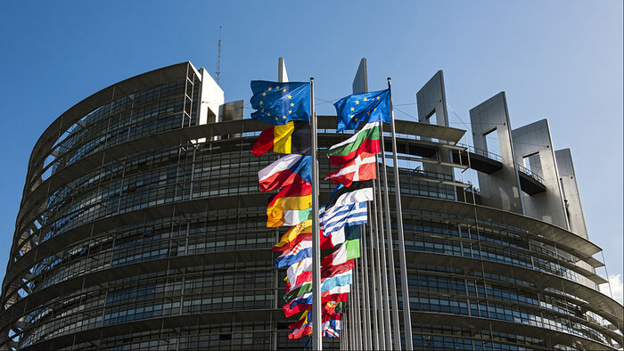 A round, modern building. European flags in front.