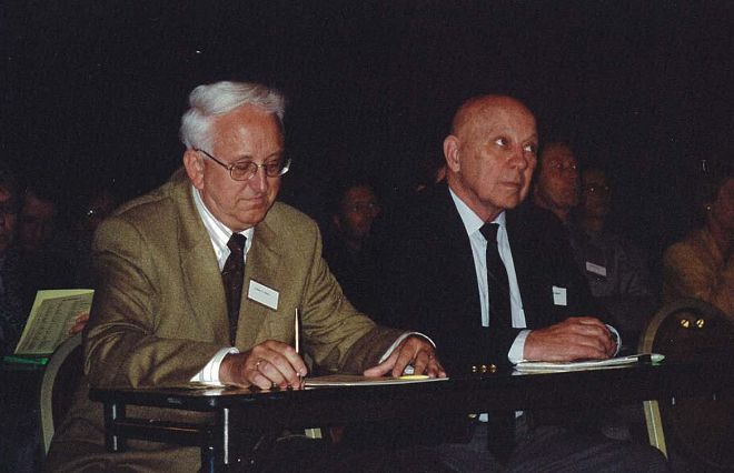 Two men in suits sitting by a table