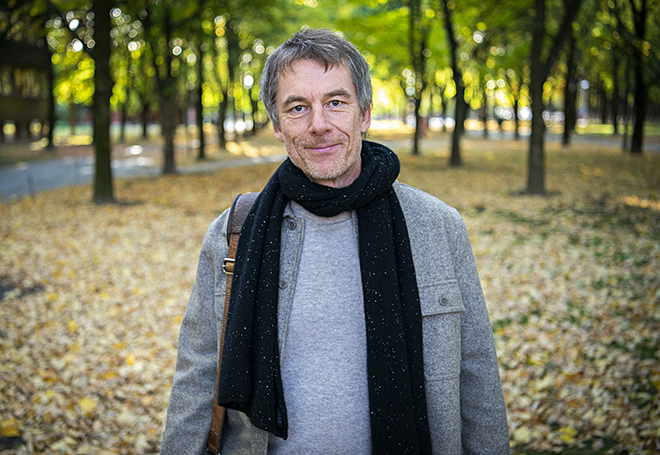 A man with a scarf standing in a park.