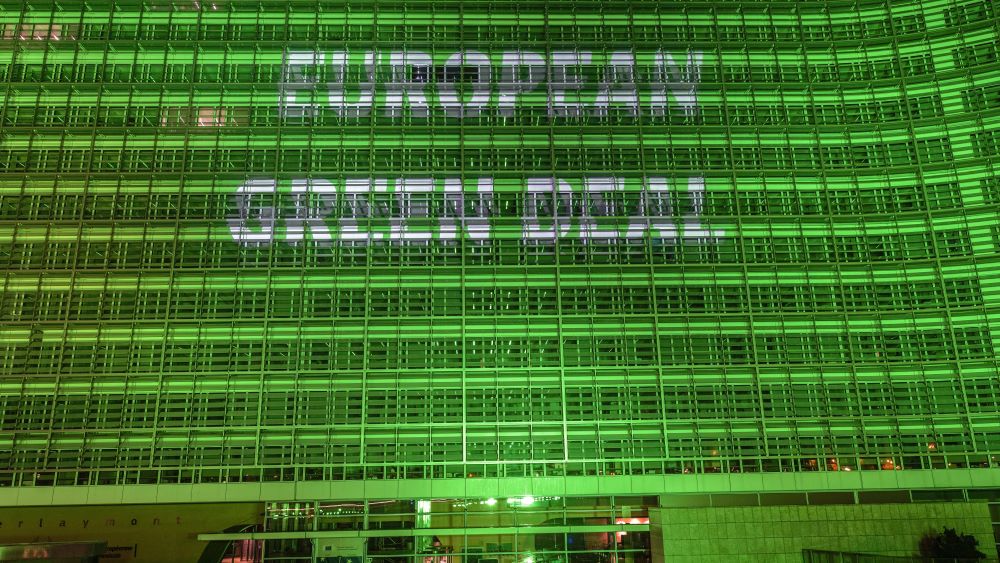 The European Commission building lit up in green showing the text "European Green Deal"
