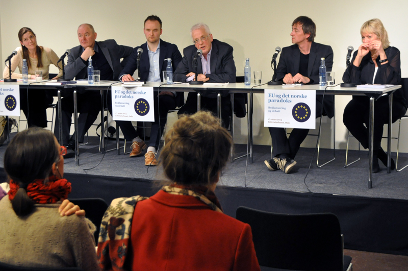 Fem personer sitter side om side ved et bord på en scene; Helene Sjursen, John Erik Fossum, Eirik Holmøyvik, Erik Oddvar Eriksen, Sten Inge Jørgensen og Kristin Clemet.