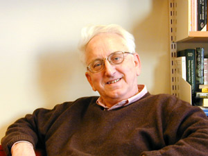 En smilende mann med hvitt hår og briller (Johan P. Olsen).