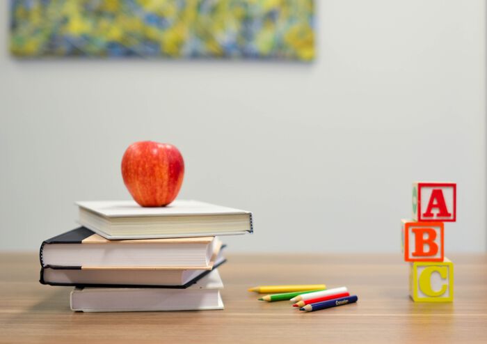 Et fotografi av et par bøker, et eple, blyanter og "ABC"-lekeblokker