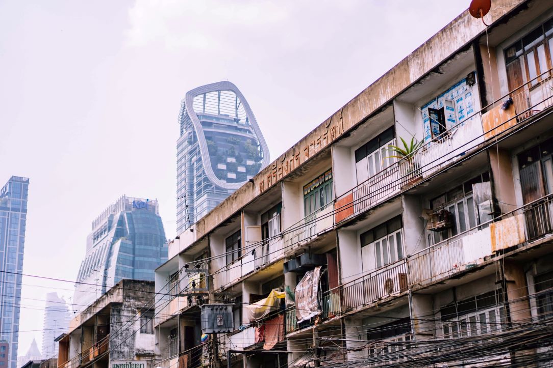 Moderne skyskrapere ruver over en sliten boligblokk i det sentrale Bankok