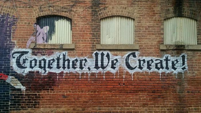 Grafitti on a brick wall. Text: Together we create!