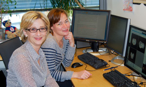 To smilende kvinner (professorene Lianne Woodward og Kristine Walhovd)ved en skrivepult.