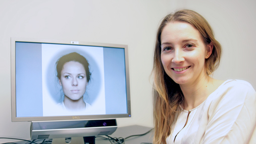 En smilende kvinne foran en dataskjerm.