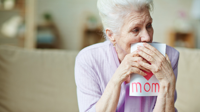 An older woman holding a card with the word "mom" on it.
