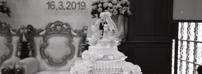 Top of a wedding cake, and a date in the background 
